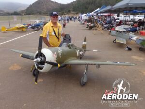 Man poses beside a model aircraft in the runway