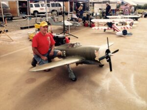 Man poses beside model aircraft during an event