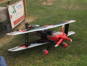 A red colored model aircraft rests in the lawn