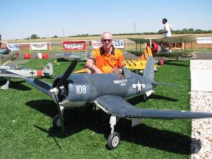 Man poses beside his model aircraft at an event