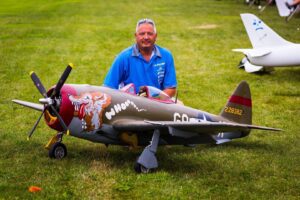 The man happily poses beside his model aircraft