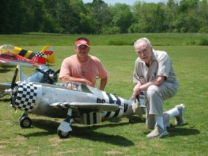 Two men posing beside their model aircraft