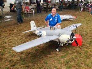 Man poses beside a light colored model aircraft